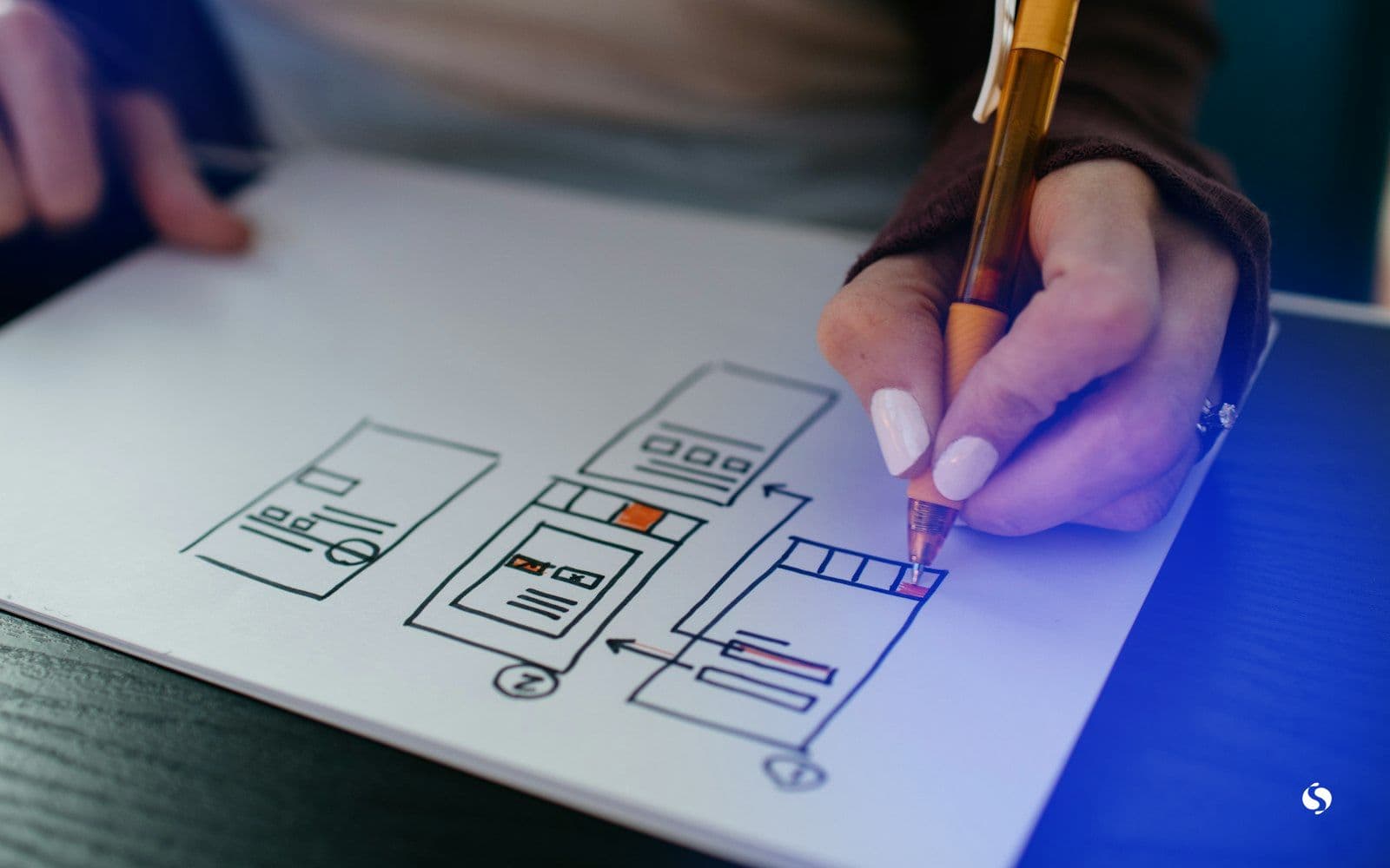 A hand sketching web page layouts on paper