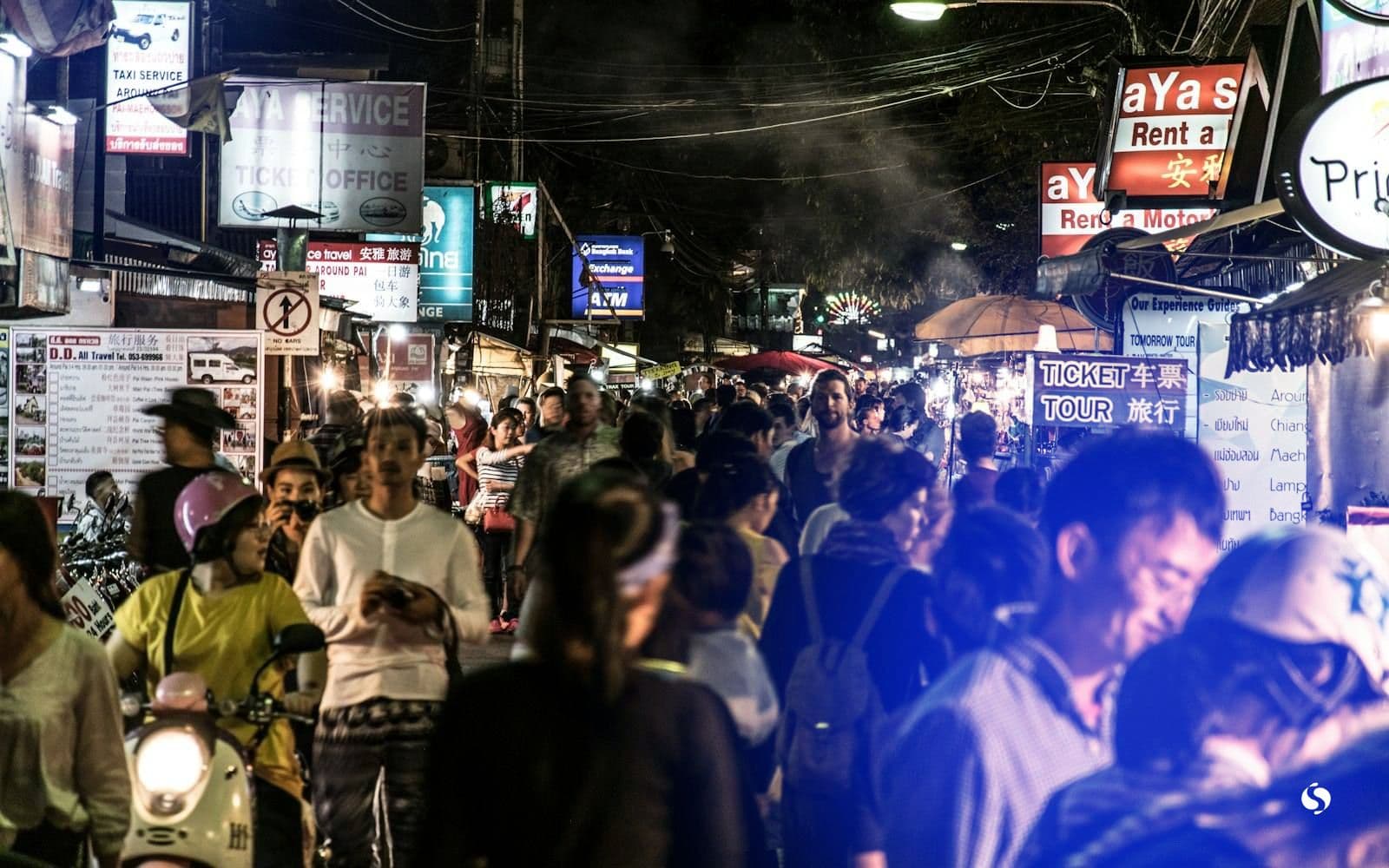 A busy night market street lit with signs
