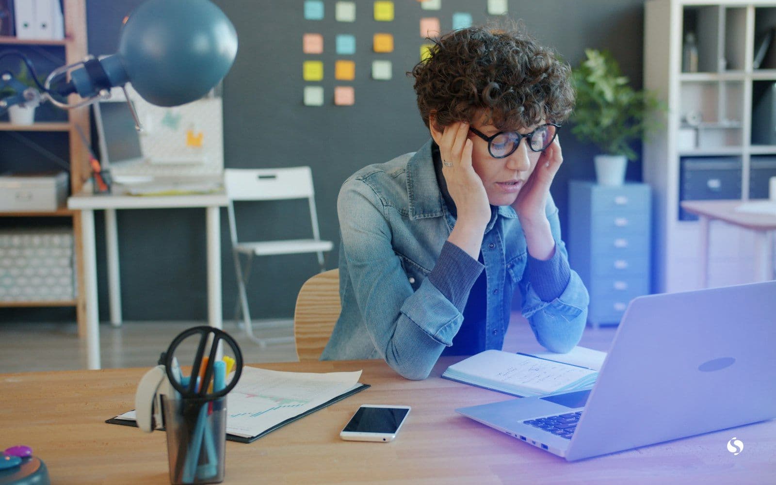 Someone looking stressed at a laptop in an office
