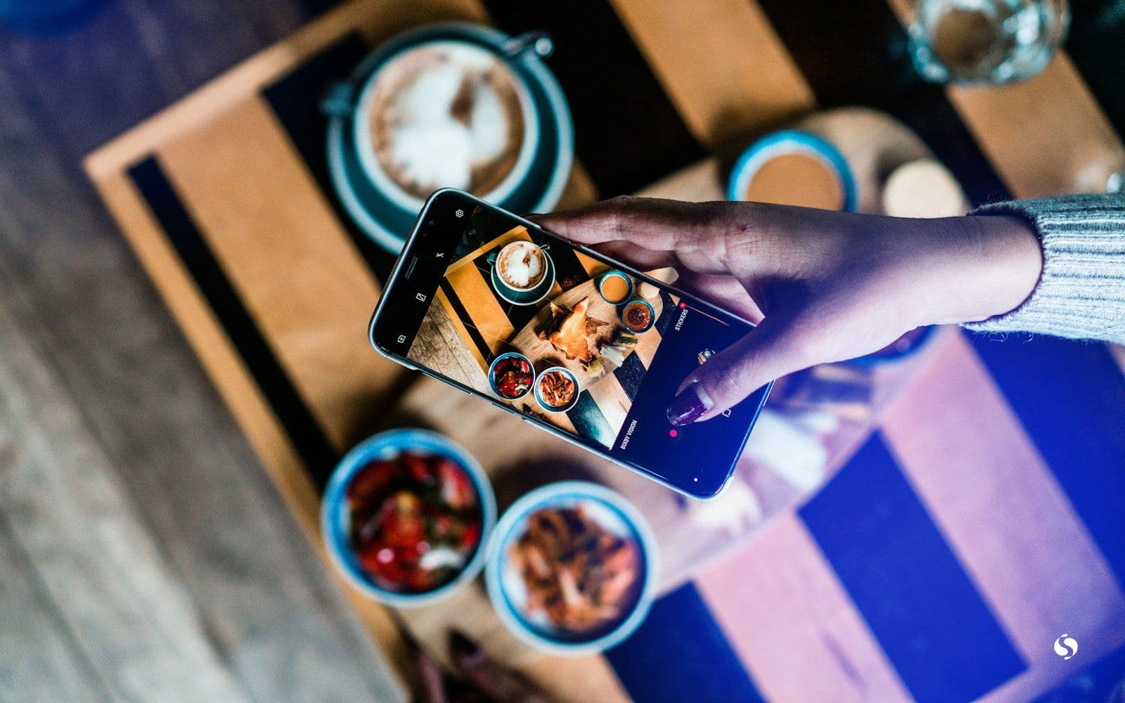 Someone photographing food at a café table with a phone